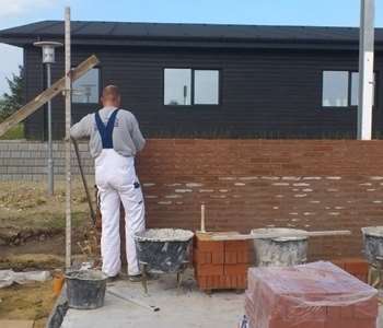 Murer i gang med at lave en tilbygning til et hus. 
